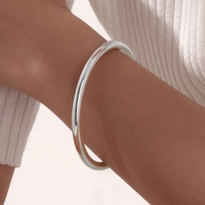Close-up of polished silver stainless steel minimalist bangle on a model's wrist