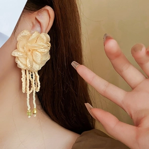 Close-up of floral fabric earrings with long champagne seed bead tassels on a model