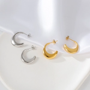 Close-up of gold and silver chunky C-shaped hoop earrings on white silk background