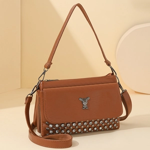 Brown leather crossbody bag with rabbit ornament and rivets on beige geometric stands