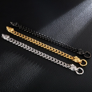 Detailed view of three punk wolf head cuban link bracelets in gold, silver, and black metal