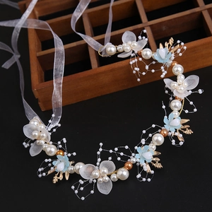 Detail of bridal headband with white pearls, blue flowers, and golden leaves on black background