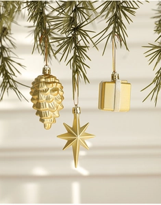 Golden pine cones, stars and gift box ornaments hanging on a green Christmas tree branch