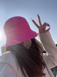 Outdoor model shot of a neon pink cotton bucket hat showing sun protection brim