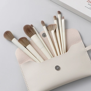 Professional 10-piece makeup brush set with off-white handles and leather storage pouch