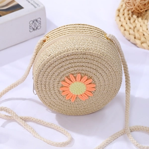 Detail of a beige woven straw bag for girls featuring a yellow daisy embroidery and zipper