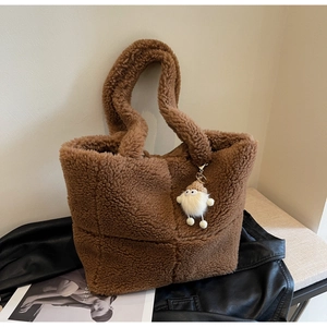 Detailansicht der braunen Teddy-Plüschtasche mit Anhänger auf schwarzer Lederjacke