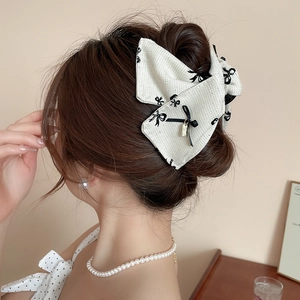 Detail of elegant cream fabric bow hair claw clip worn on model with retro Korean style