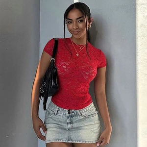 T-shirt femme en dentelle rouge et jupe en jean sur fond de mur texturé gris