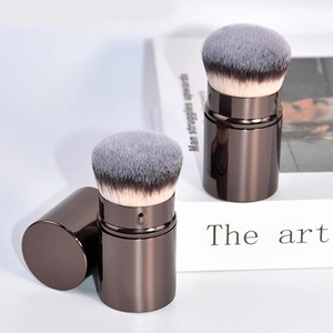 Macro view of retractable foundation brush with soft bristles and brown metallic cap