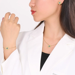 Detailed view of sunflower jewelry set with blue evil eye on model, golden steel finish