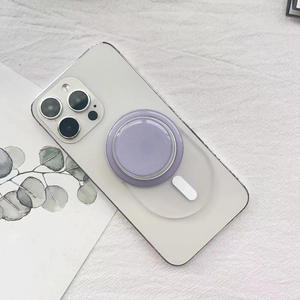 Dettaglio del supporto MagSafe circolare viola fissato sul retro di un iPhone bianco
