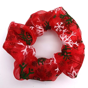 Detailed view of red mesh scrunchie with white and green Christmas snowflake pattern