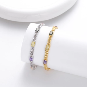 Dettaglio macro di bracciali a catena cubana in oro e argento con zirconi colorati