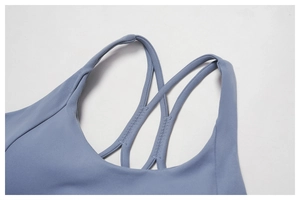 Close-up of dual criss-cross shoulder straps on a dusty blue sports yoga bra