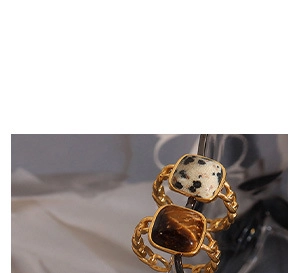 Close-up of vintage gold chain rings with square marble and tiger eye stone inlay