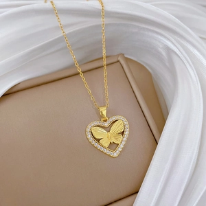 Close-up of a gold heart butterfly pendant with sparkling crystals on white silk fabric