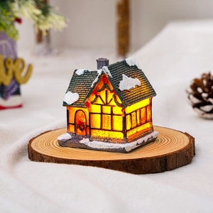 Macro view of a glowing resin Christmas snow house on a wooden base with festive lights