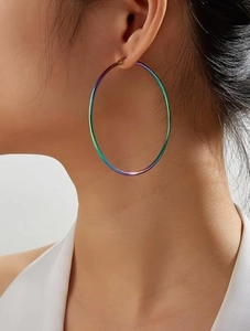 Macro detail of large gradient rainbow metallic hoop earrings worn by a female model