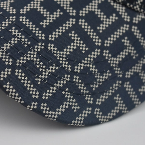 Close-up of navy baseball cap brim with white H monogram pattern and neat stitching