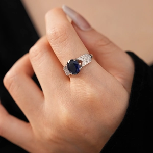 Gros plan d'une bague feuille en argent avec une grande pierre bleue et des zircons brillants