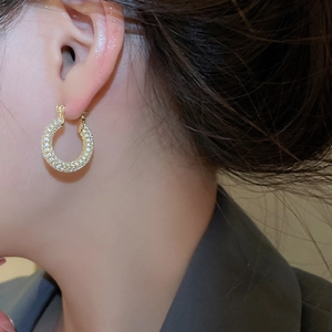 Close-up of gold plated U-shaped hoop earrings with sparkling cubic zirconia on a model