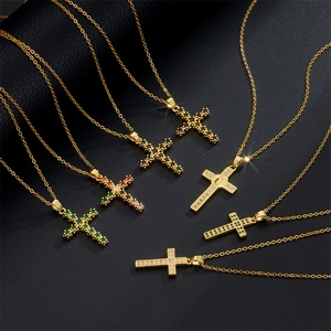 Golden cross necklaces with colorful zircon stones on textured black background