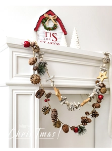 Rustic Christmas wall decor with natural pine cones, wood stars, and red berries on jute rope