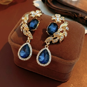Gros plan de boucles d'oreilles vintage dorées avec pendentif saphir bleu goutte