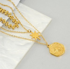 Detail of layered gold star and coin pendant necklace on elegant marble background