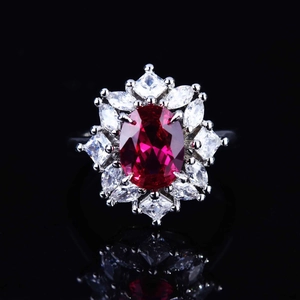 Macro view of luxurious silver ring with oval red gemstone and radiant cluster setting