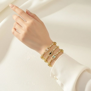 Detail of layered gold evil eye bracelets with cubic zirconia inlay on female wrist