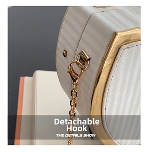 Macro detail of the detachable golden lobster clasp and ribbed texture of this white bag