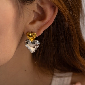 Zweifarbige Herzohrringe aus Gold und Silber am Modell mit glänzendem Finish