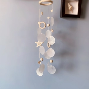 Handmade wooden starfish and seashell wind chime hanging against a calm blue wall