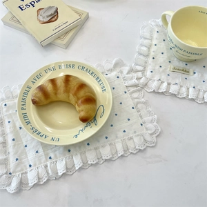 Detail of white lace coasters with blue heart pattern and cream ceramic tableware set