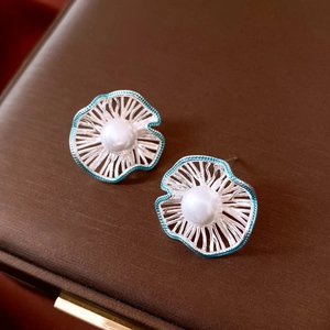 Detailed close-up of blue hollow lotus leaf earring with white pearl center inlay