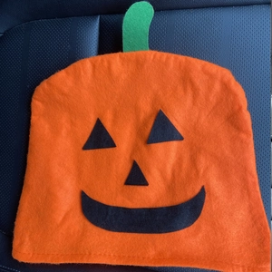 Close-up of Halloween pumpkin felt chair cover with orange finish and green stem detail