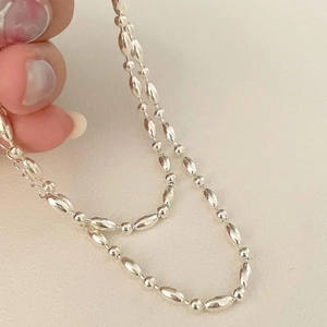 Detail of 925 sterling silver beaded necklace with rice-shaped links and small round beads