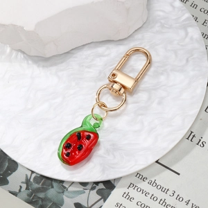 Miniature glass watermelon slice keychain with gold metal clasp on white stone decor