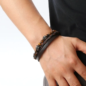 Detail of multi-layer bracelet featuring tiger eye beads, silver skull, and braided leather