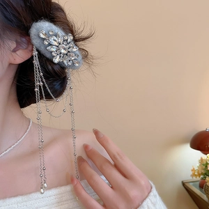 Detail of grey velvet hair clip with sparkling rhinestones and elegant pearl tassels