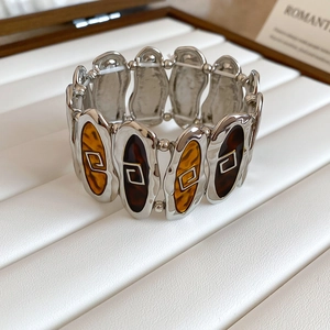 Detail view of vintage oval resin patches and silver geometric patterns on elastic bracelet