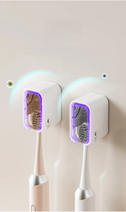Detail of wall-mounted UV toothbrush sanitizer with dust cover in white and champagne