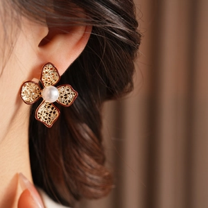 Nahaufnahme von Vintage-Blumenohrringen mit goldenen Blütenblättern und einer großen Perle