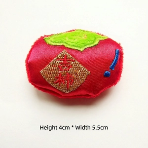 Detailed view of red plush persimmon doll with gold 'Ji' embroidery, size 4x5.5cm