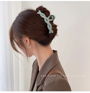 Detail view of a large light green twisted claw clip worn by a model in a hair twist