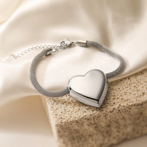 Detailed view of silver heart pendant with mesh woven metal chain on stone base