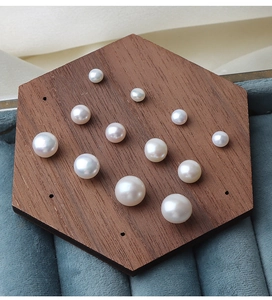 Macro shot of assorted natural freshwater pearls on a hexagonal wooden display tray