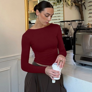Dettaglio del top attillato rosso scuro a maniche lunghe in un ambiente accogliente di caffè